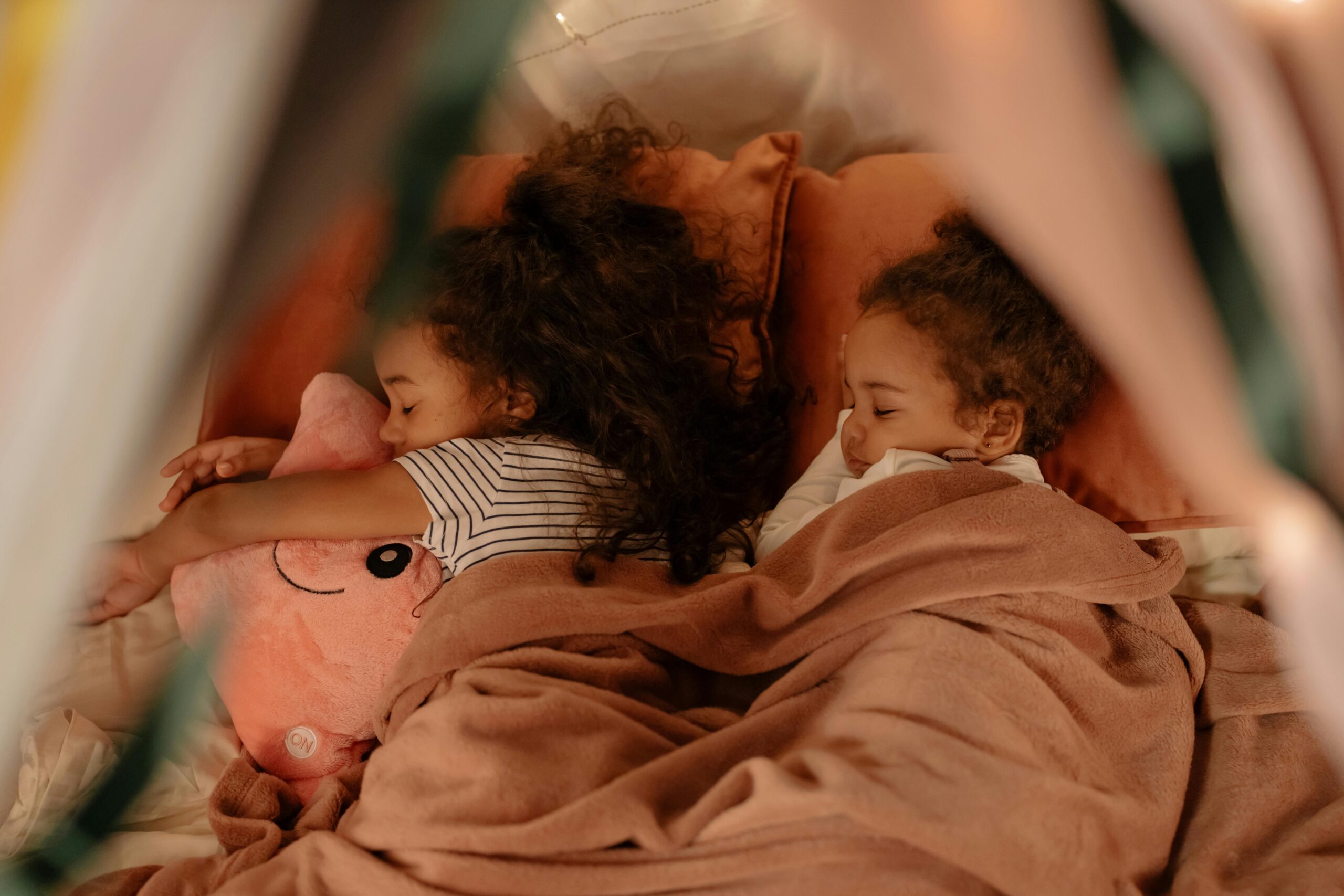 Blackout blinds Two young children peacefully sleeping under cozy blankets, sharing a tender moment.